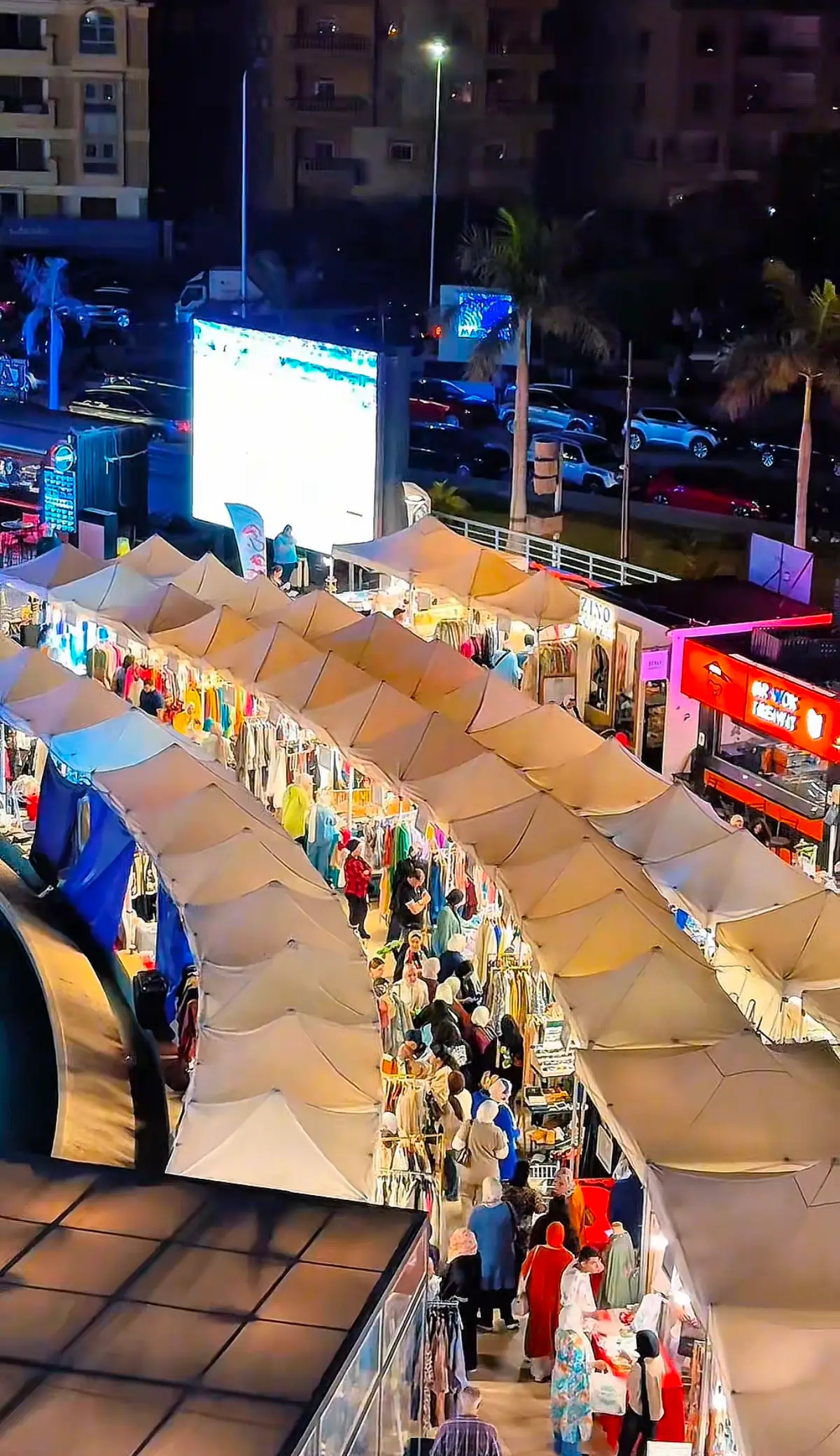 Evening crowd walking between lit market stalls at a Volume bazaar